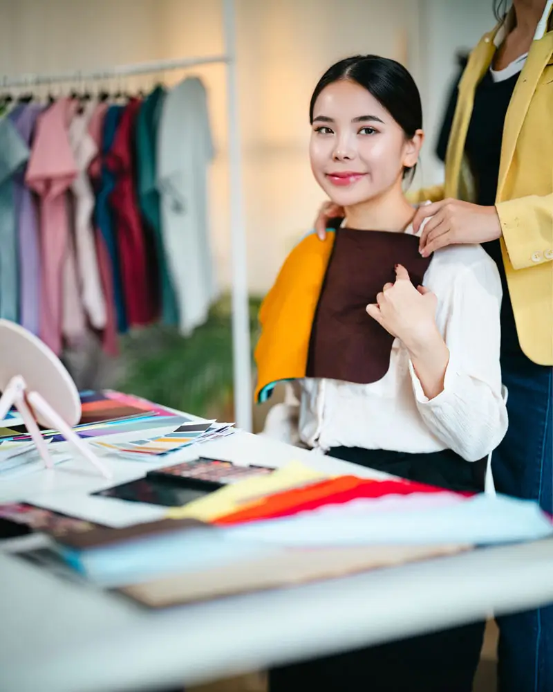 A woman stands beside a table, examining a piece of fabric laid out in front of her.
