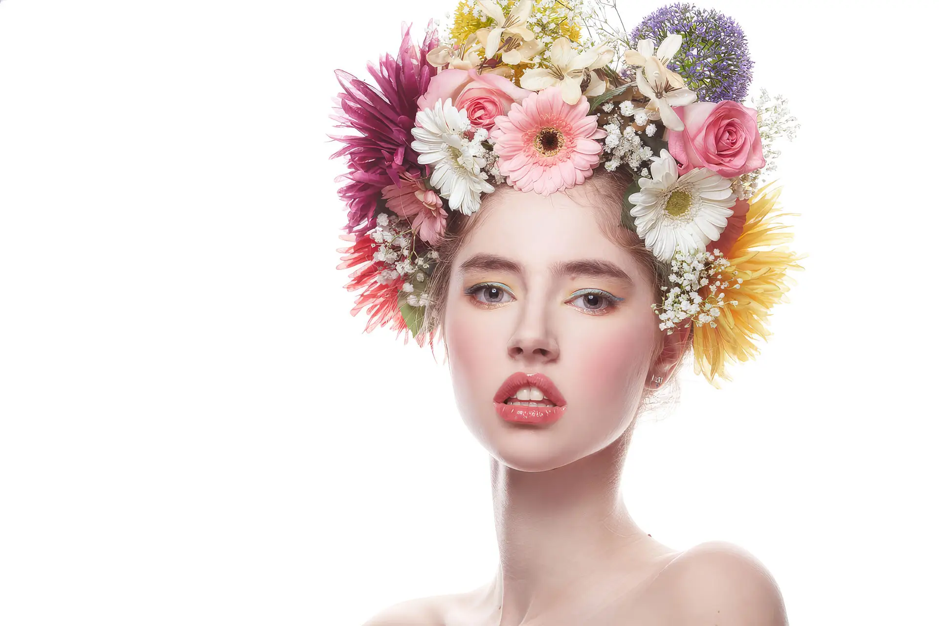 A beautiful woman with a serene expression, adorned with vibrant flowers in her hair, surrounded by a soft, natural background.